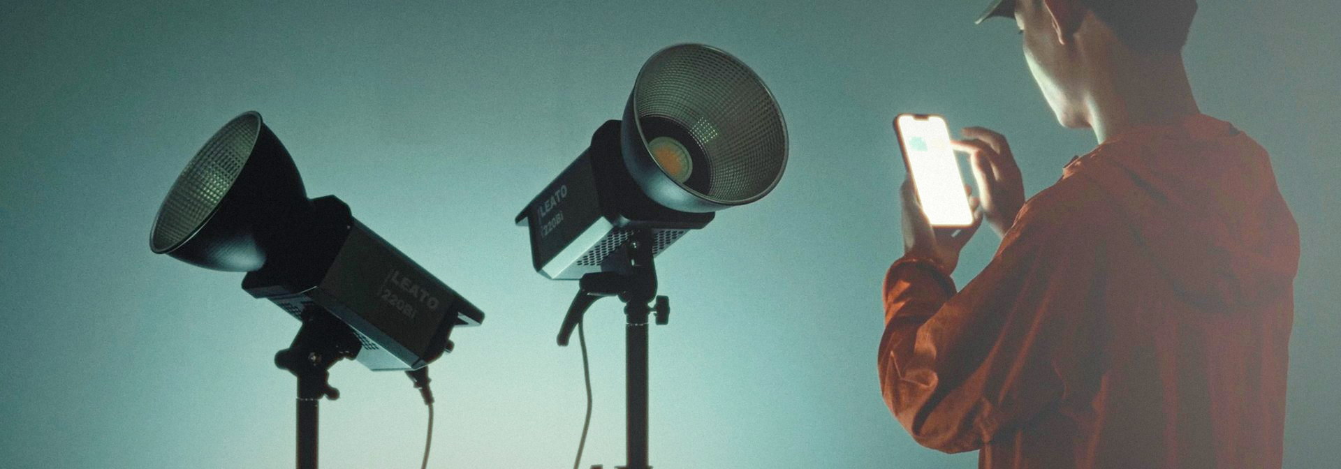 A photographer adjusting two LEATO LED COB lights from the Golden Eagle control app